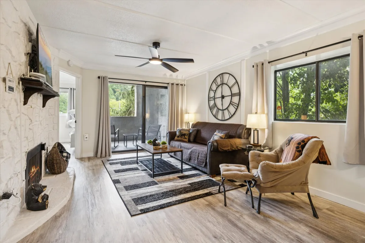 A cozy living space is shown with a comfortable sofa, armchair, and a sliding glass door that hints at an easy transition between indoor and outdoor leisure. The inviting furnishings make for a welcoming environment that resonates with the idea of relaxing after pool time.