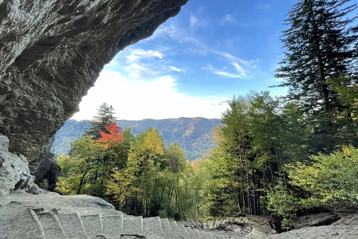 A sweeping view of a rocky overhang framing a mountain range with vibrant autumn foliage. The landscape is bathed in the warm glow of sunset, creating a serene and romantic mood that invites exploration and moments of quiet togetherness.