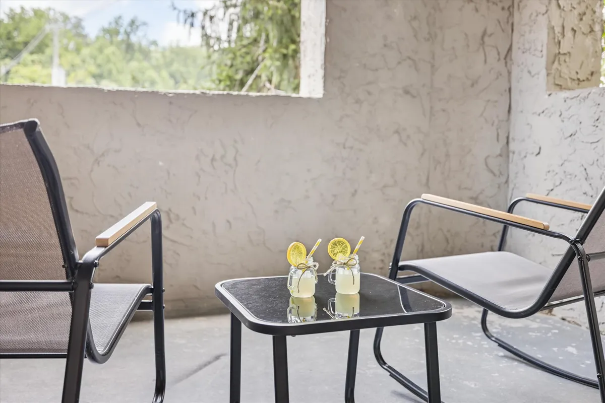 A cozy outdoor setup with two glasses of lemonade on a black table and two chairs, positioned to enjoy the view. The scene suggests a tranquil and refreshing space perfect for relaxing or socializing on the balcony.